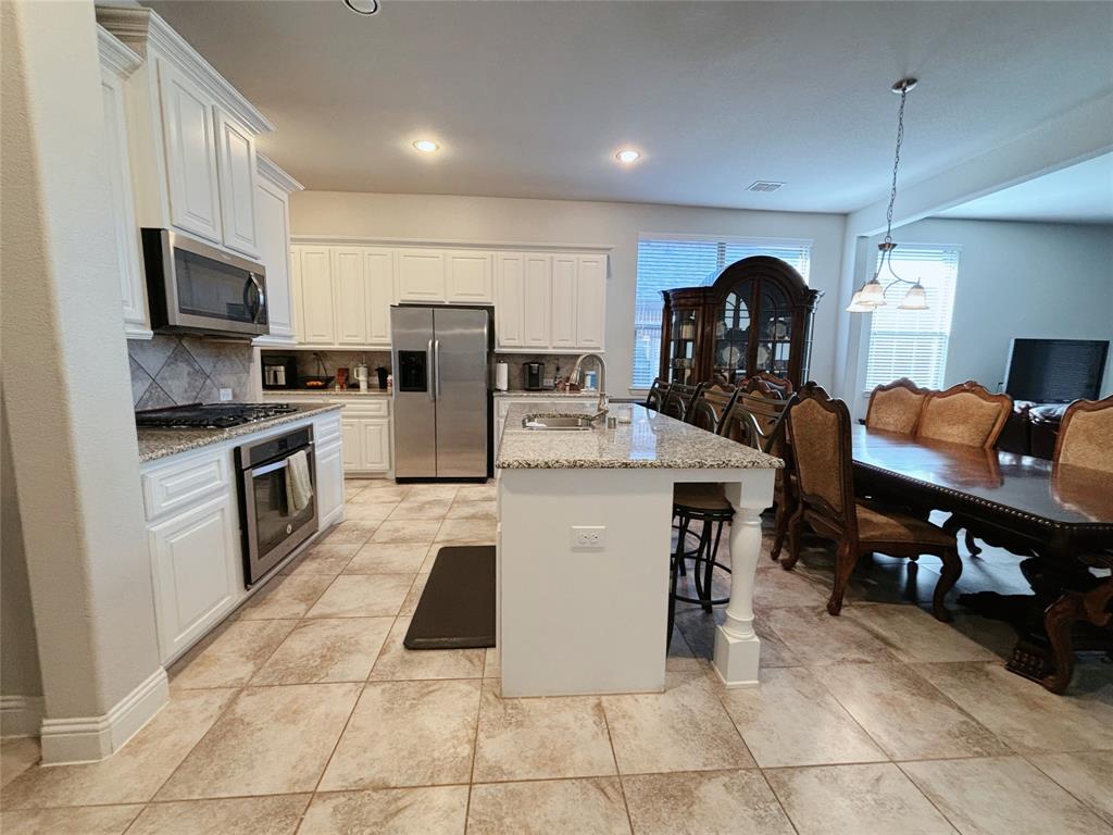 556 England Street Fate, TX 75189 - Photo 5 of 14 a kitchen with stainless steel appliances granite countertop a stove top oven a sink a counter top space and cabinets