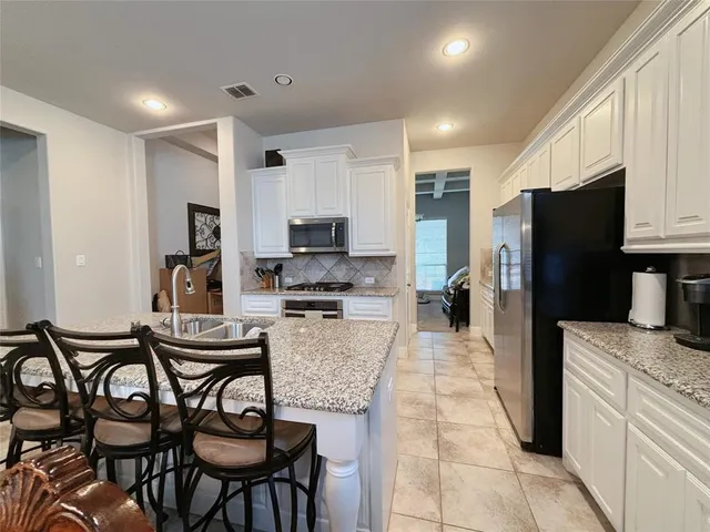 a kitchen with stainless steel appliances kitchen island granite countertop a refrigerator and microwave