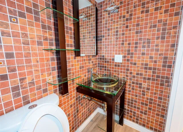 a bathroom with a sink a toilet a mirror and shower