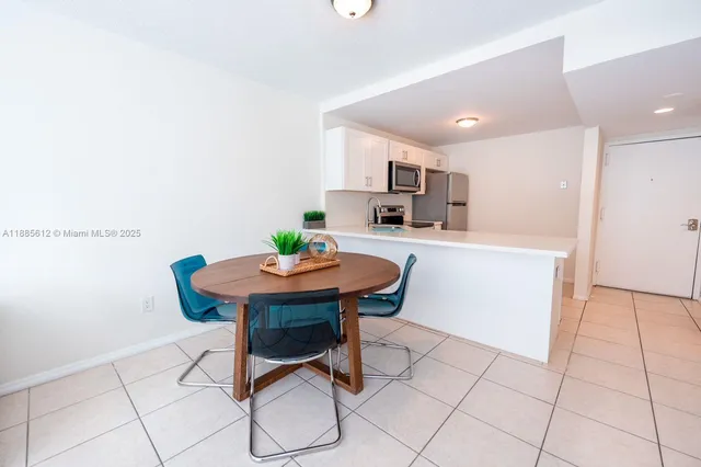 a room with a table chairs and a kitchen view