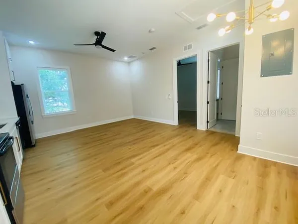 a view of an empty room with wooden floor and closet