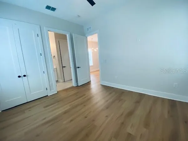 a view of an empty room with wooden floor and a window