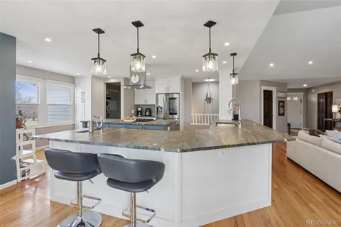 a large kitchen with granite countertop a sink and a chandelier