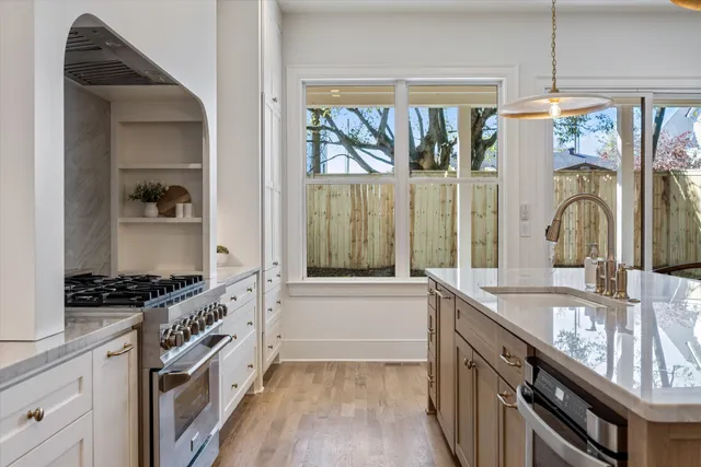 a kitchen with stainless steel appliances granite countertop a sink a stove and a wooden floors