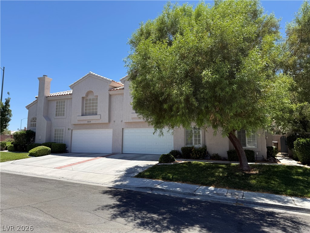 A well-maintained stucco facade with a two-car garage and mature landscaping welcomes visitors.