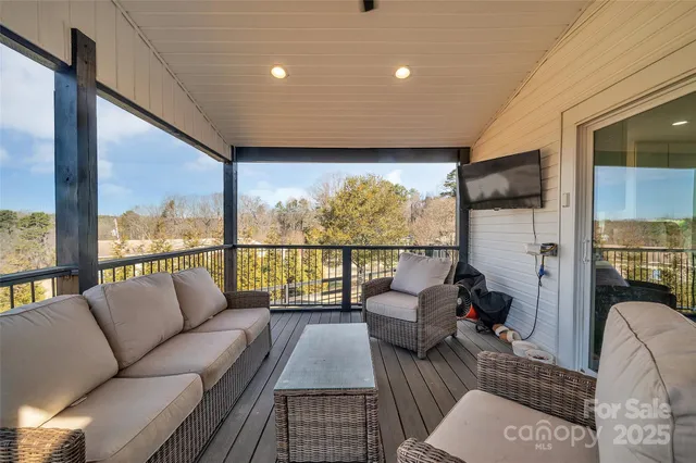 a living room with furniture floor to ceiling window and a flat screen tv