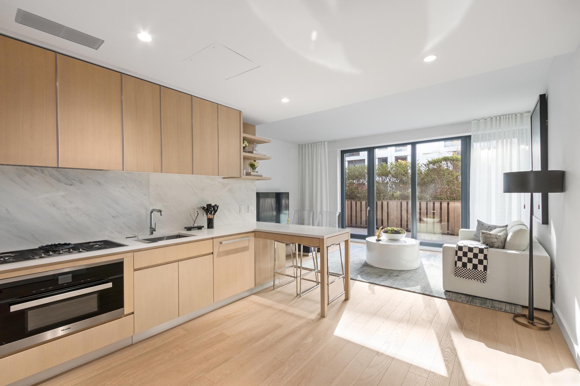 500 West 45th Street, Unit 230 Manhattan, NY 10026 - Photo 2 of 16 a kitchen with a table chairs stove and cabinets