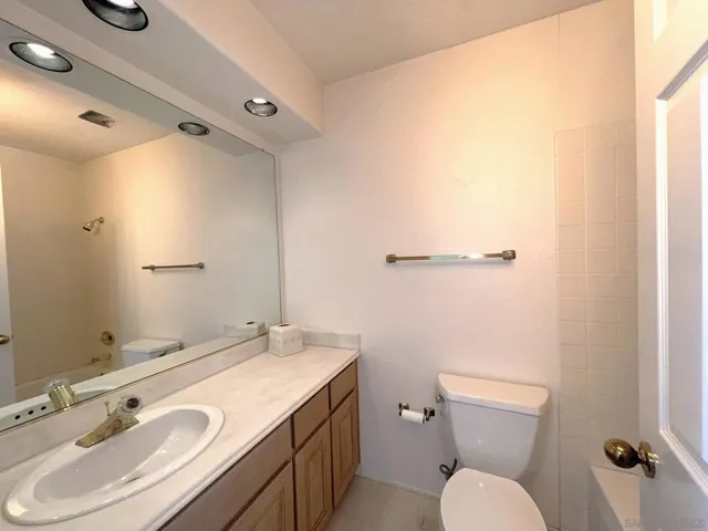a bathroom with a granite countertop toilet sink and mirror
