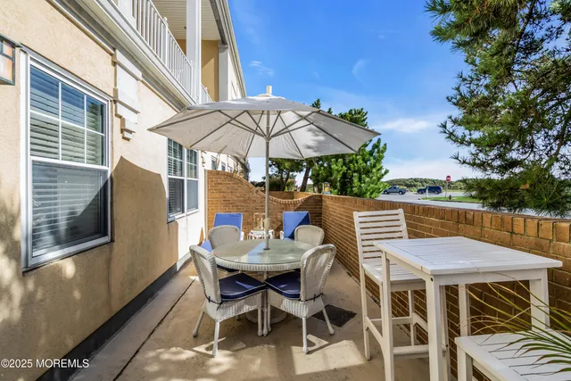 a view of a patio with table and chairs under an umbrella with barbeque grill and wooden fence