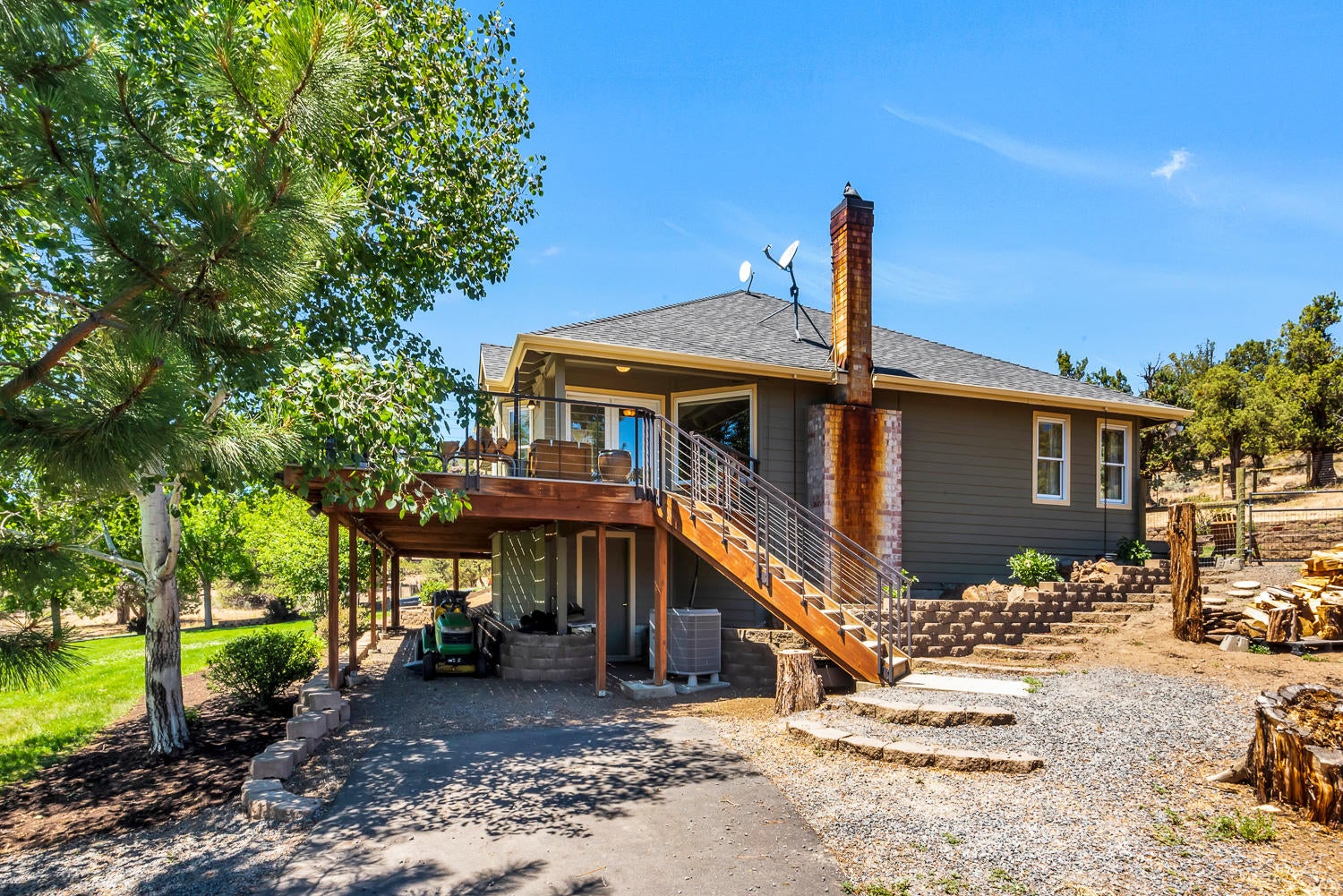 19310 Dayton Road Bend, OR 97703 - Photo 22 of 40 East side of house with stairs from deck leading to basement. Under deck storage for lawn mowers, kayaks, yard tools, etc.