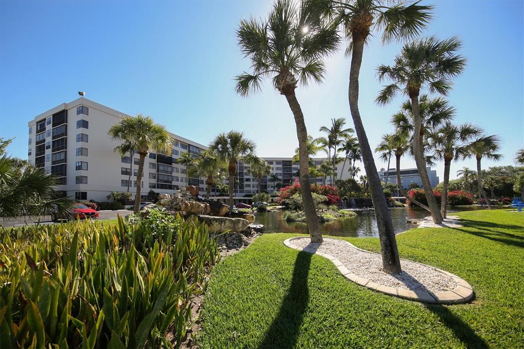 5855 Midnight Pass Road, Unit 420 Sarasota, FL 34242 - Photo 29 of 53 a view of a garden with a building and palm trees
