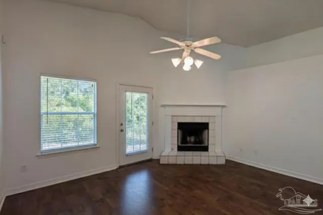 an empty room with wooden floor fireplace and a window