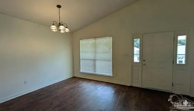 an empty room with wooden floor and chandelier