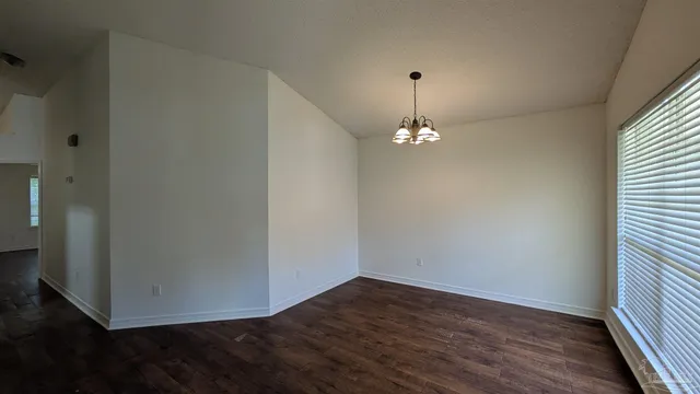 a view of an empty room with wooden floor fireplace and a window