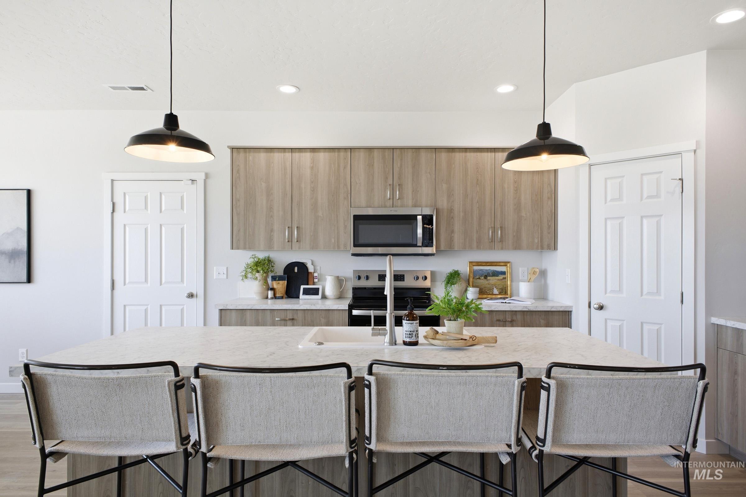 1641 Dyer Street Middleton, ID 83644 - Photo 13 of 29 Kitchen with light wood finished floors, a kitchen bar, an island with sink, stainless steel appliances, and light stone countertops