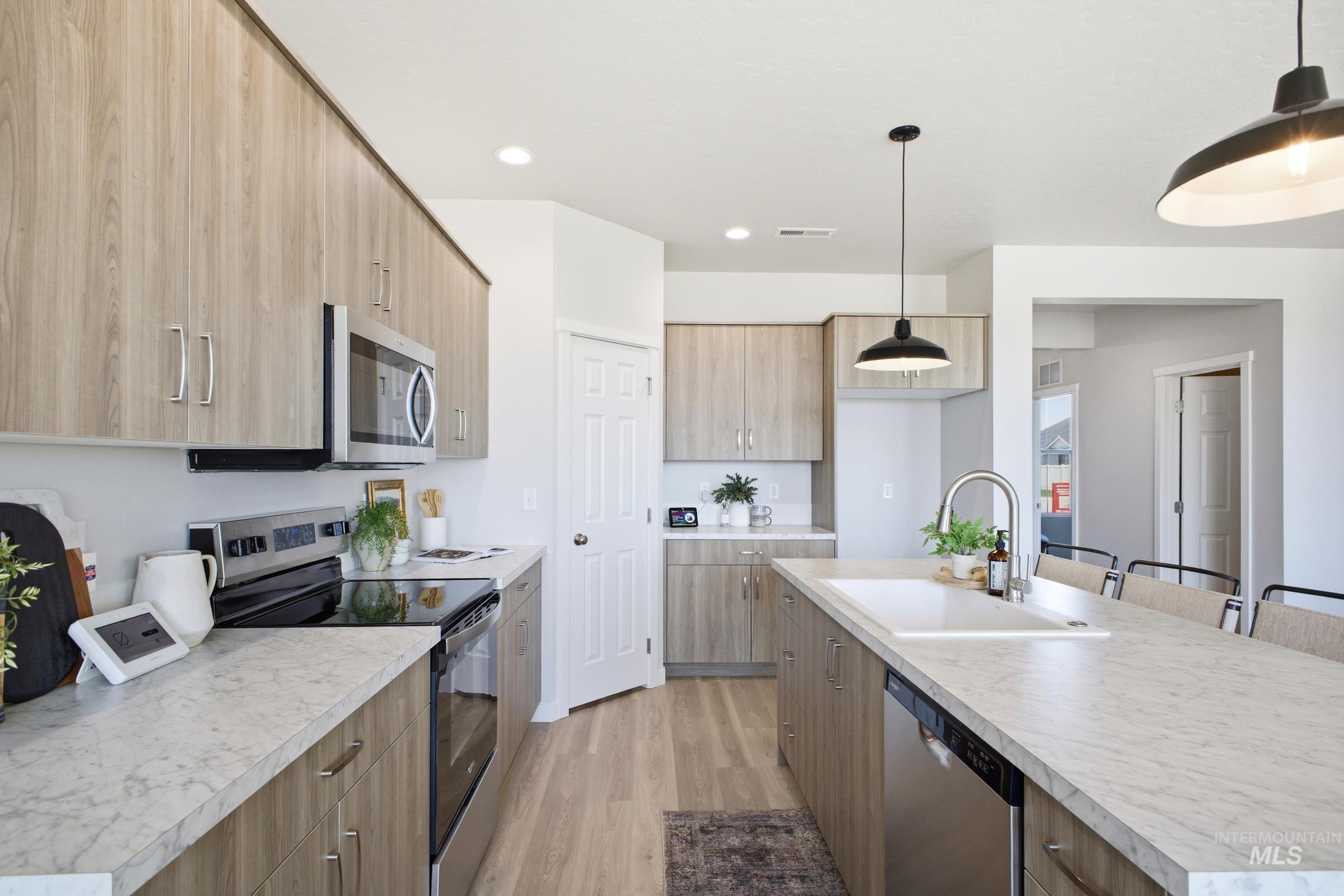 1641 Dyer Street Middleton, ID 83644 - Photo 15 of 29 Kitchen featuring stainless steel appliances, a center island with sink, light countertops, light wood finished floors, and a kitchen bar