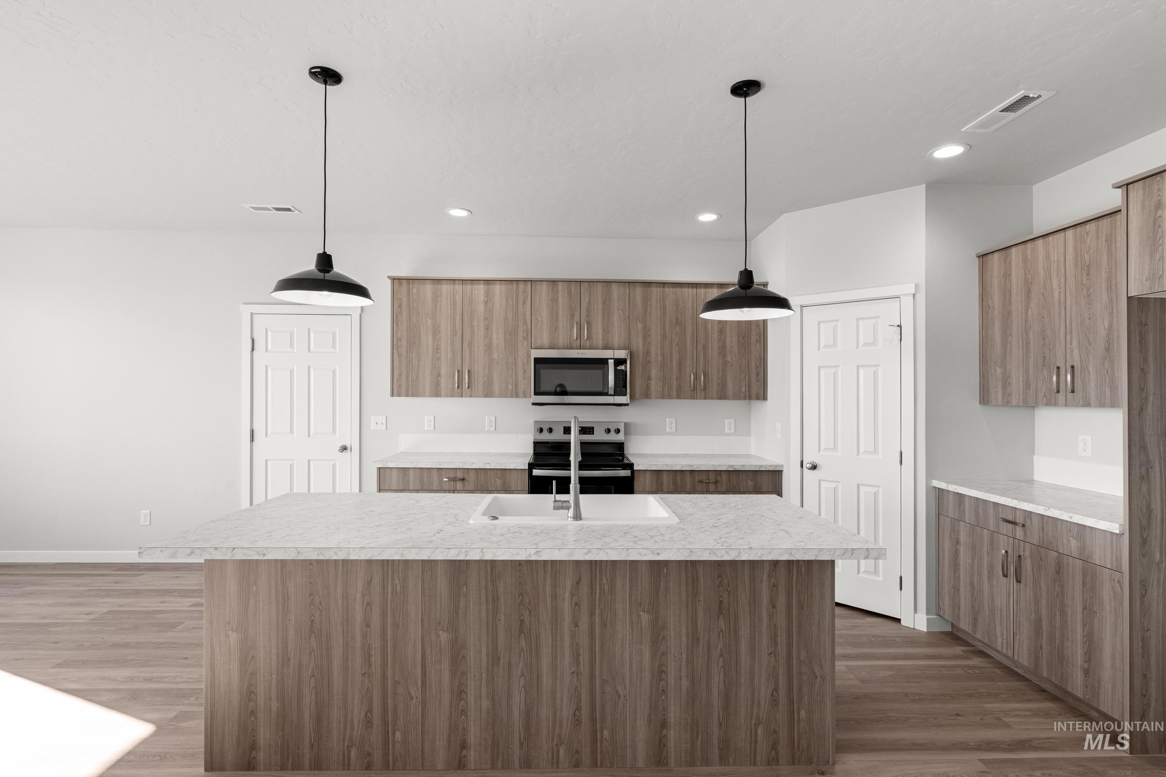 1641 Dyer Street Middleton, ID 83644 - Photo 4 of 28 Kitchen featuring an island with sink, dark wood finished floors, hanging light fixtures, stainless steel appliances, and wood finish cabinets