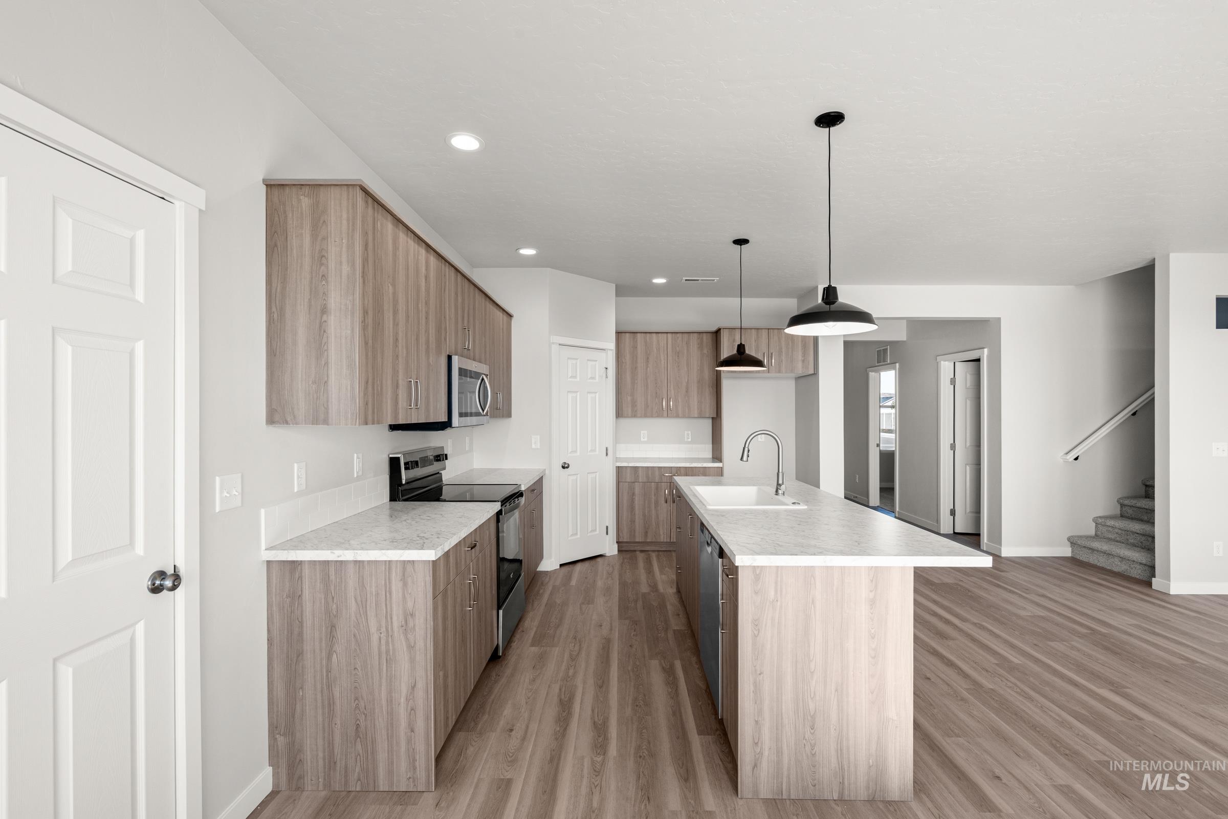 1641 Dyer Street Middleton, ID 83644 - Photo 6 of 28 Kitchen featuring an island with sink, modern cabinets, stainless steel appliances, light countertops, and hanging light fixtures