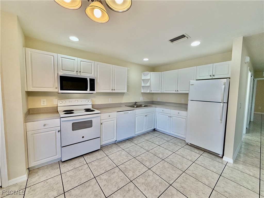 4739 28th Street Southwest Lehigh Acres, FL 33973 - Photo 5 of 14 a kitchen with a refrigerator a microwave and cabinets