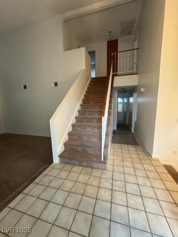 713 Rusty Spur Drive Henderson, NV 89014 - Photo 4 of 15 Stairs with tile patterned flooring, a high ceiling, and carpet flooring