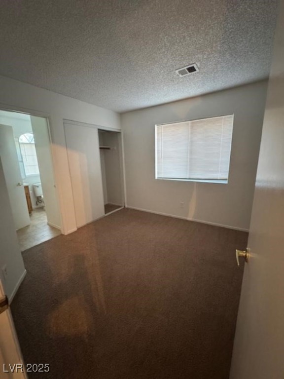 713 Rusty Spur Drive Henderson, NV 89014 - Photo 9 of 15 Unfurnished bedroom with multiple windows, a closet, carpet flooring, and a textured ceiling