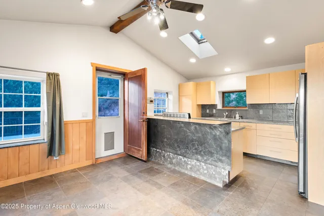 a large kitchen with kitchen island granite countertop a refrigerator a oven a sink and white cabinets