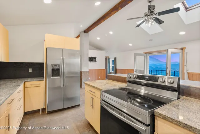 a kitchen with stainless steel appliances granite countertop a stove a refrigerator a sink a stove and white cabinets