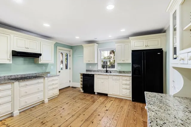 a kitchen with granite countertop a refrigerator and a stove top oven