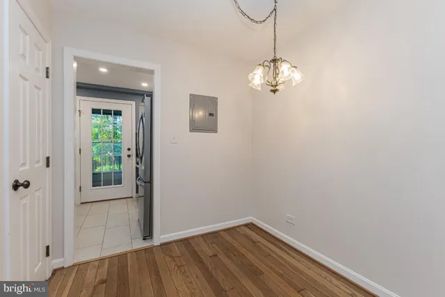a view of a hallway with wooden floor and chandelier