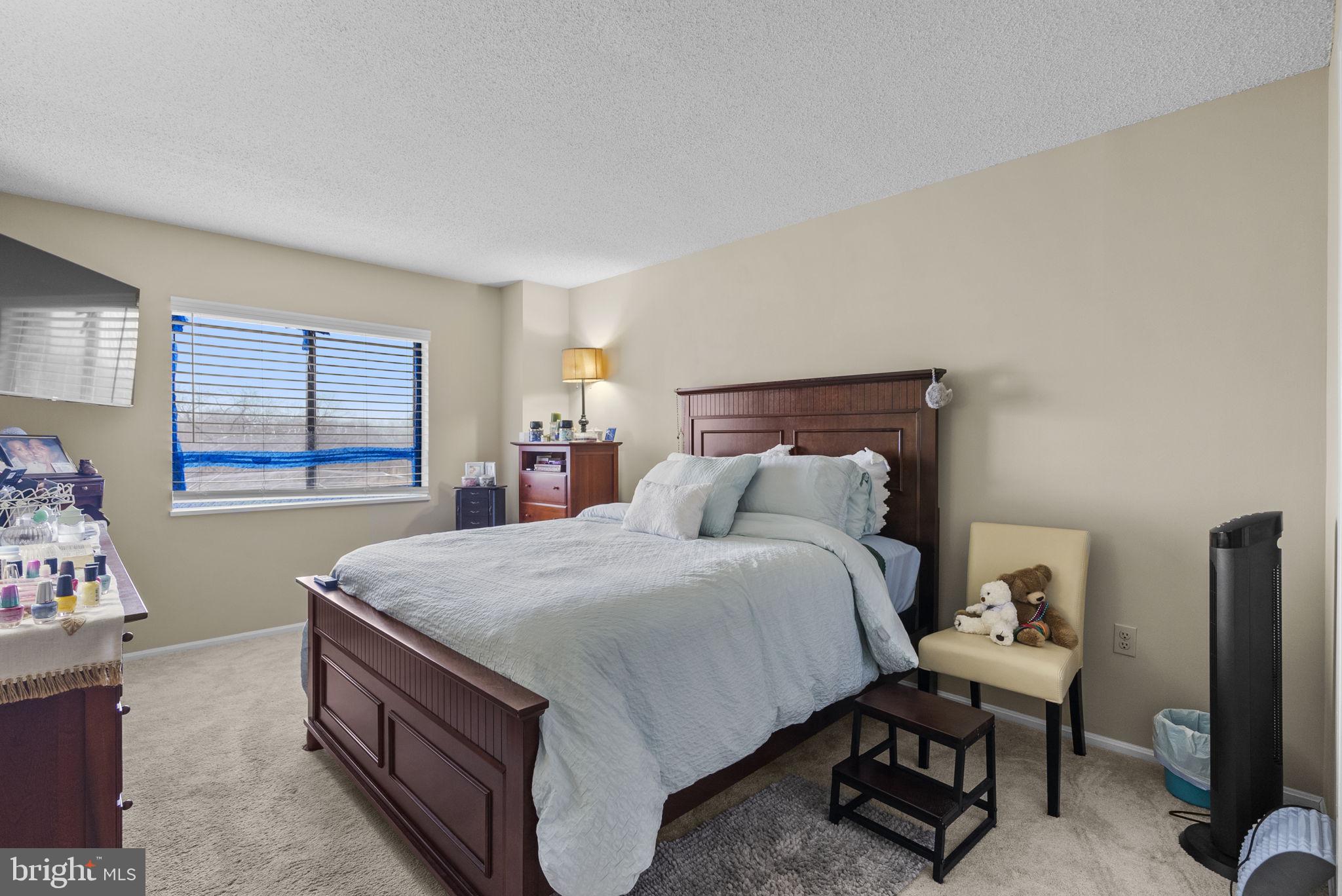 15101 Interlachen Drive, Unit 1705 Silver Spring, MD 20906 - Photo 11 of 17 a bedroom with a bed and a dresser next to a window