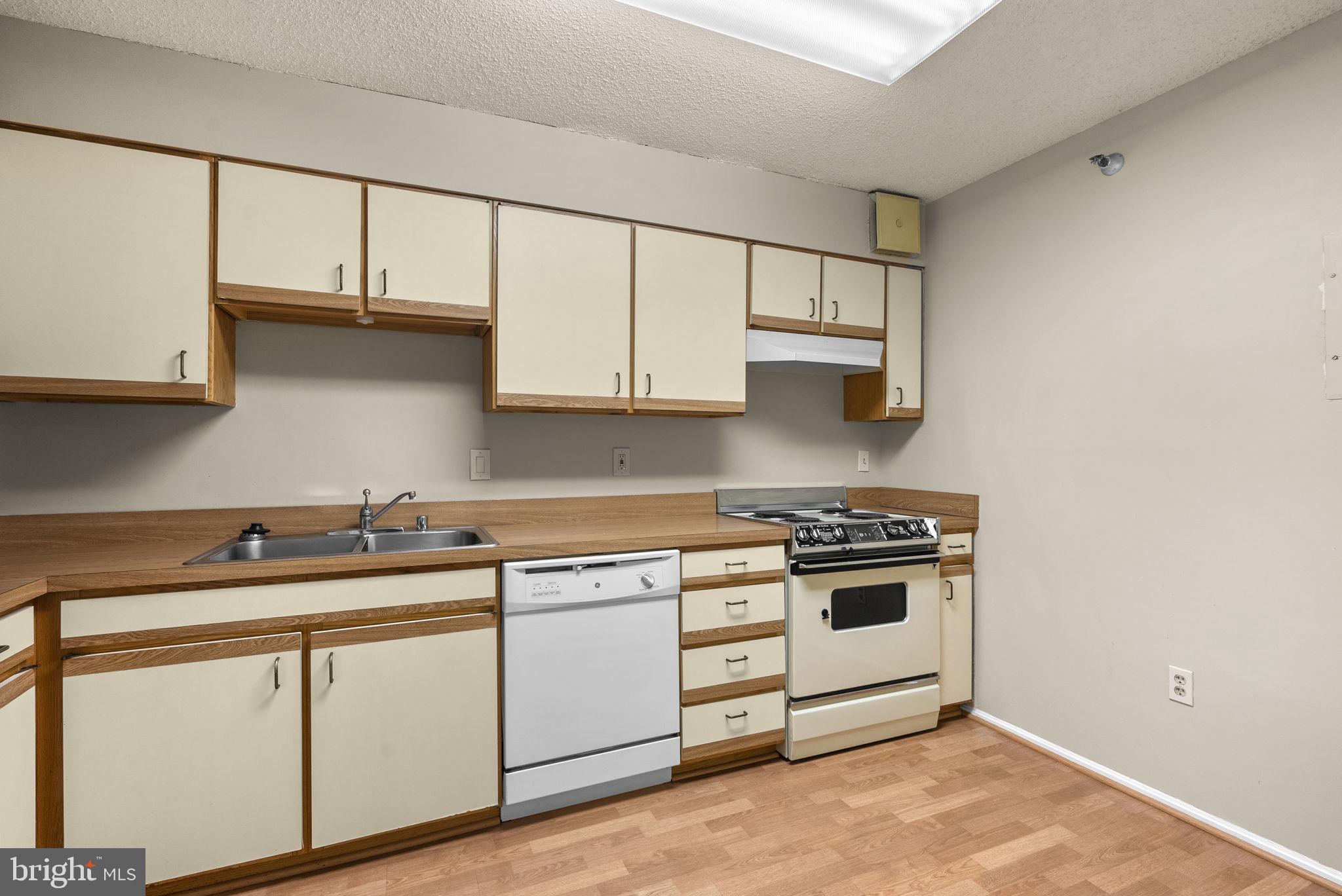 15101 Interlachen Drive, Unit 1705 Silver Spring, MD 20906 - Photo 7 of 17 a kitchen with white cabinets and white appliances