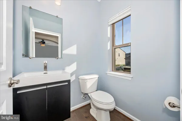 a bathroom with a toilet a sink a mirror and a window
