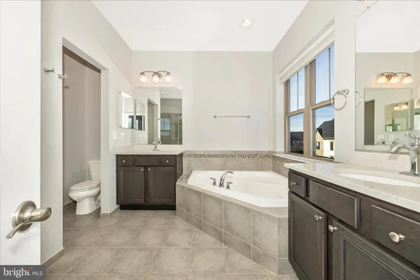 a bathroom with a tub a sink and a large mirror