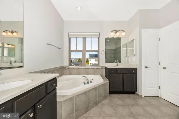 a spacious bathroom with a tub sink and mirror