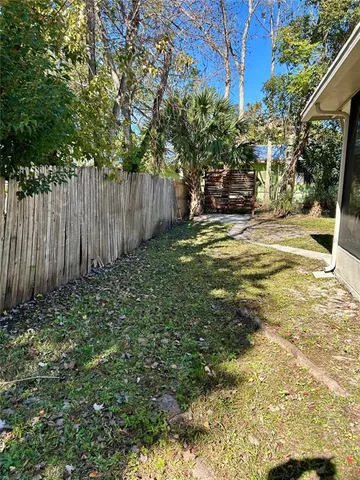 a view of a yard with plants and large trees