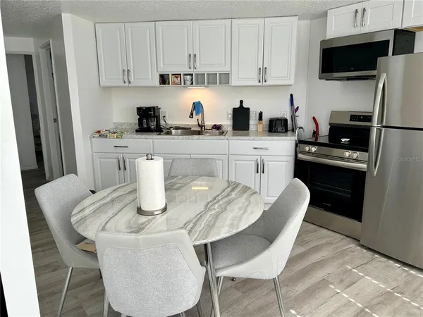 a kitchen with stainless steel appliances granite countertop a dining table chairs microwave and sink