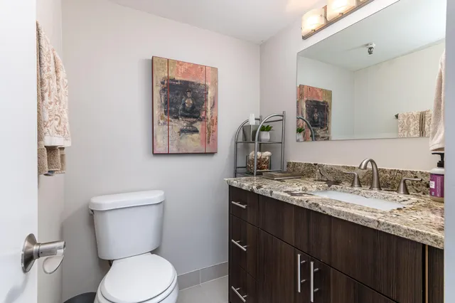 a bathroom with a granite countertop toilet sink and mirror