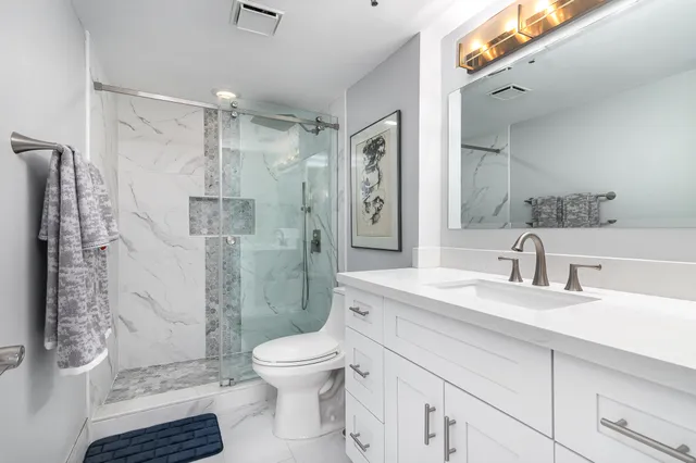 a bathroom with a granite countertop sink toilet and shower