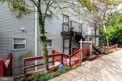 a view of a house with wooden deck stairs and a large tree