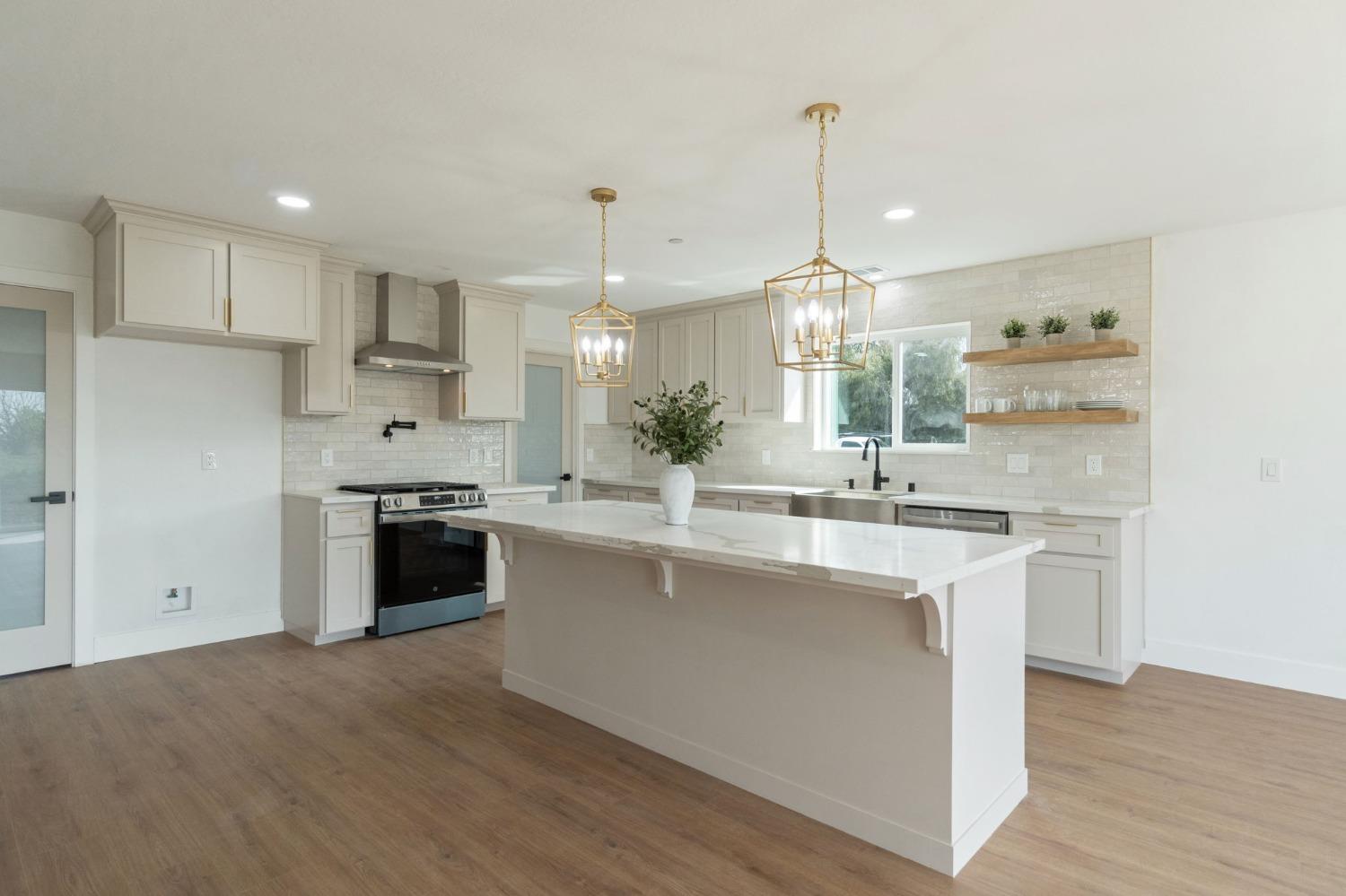 25918 Tanforan Drive Madera, CA 93638 - Photo 11 of 37 a kitchen with stainless steel appliances kitchen island granite countertop a sink a stove a refrigerator and white cabinets
