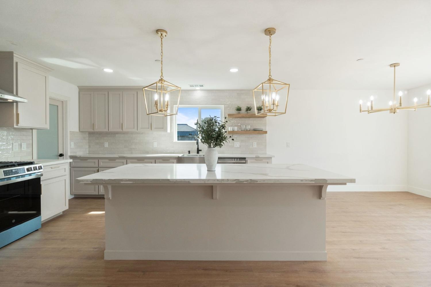 25918 Tanforan Drive Madera, CA 93638 - Photo 13 of 37 a kitchen with kitchen island granite countertop a sink a counter space appliances and cabinets