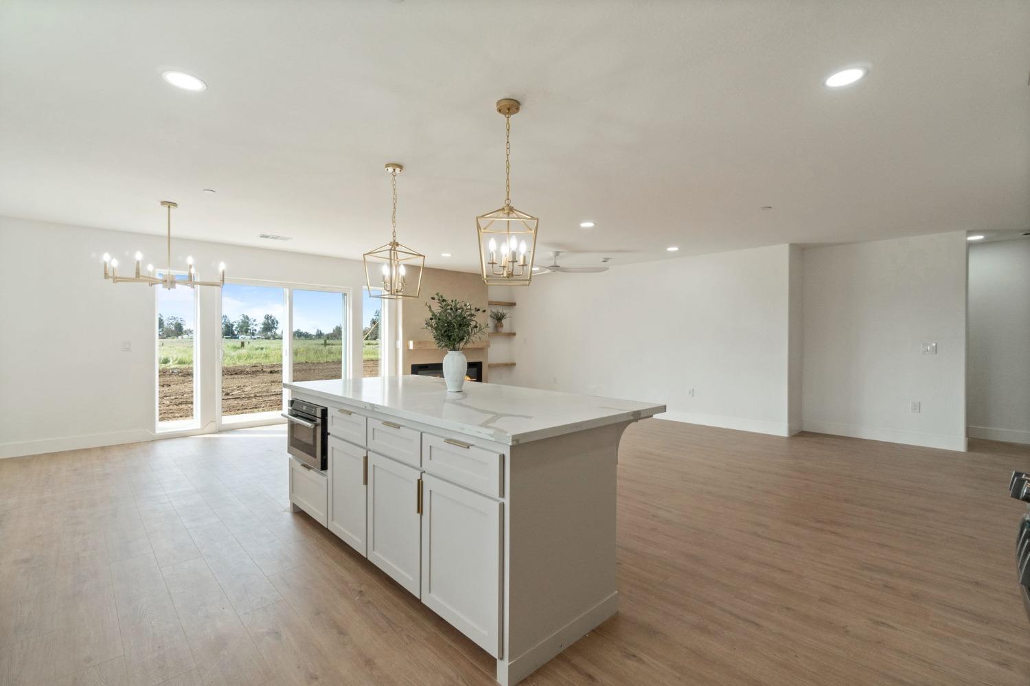 25918 Tanforan Drive Madera, CA 93638 - Photo 14 of 37 a large kitchen with granite countertop a stove and a wooden floor