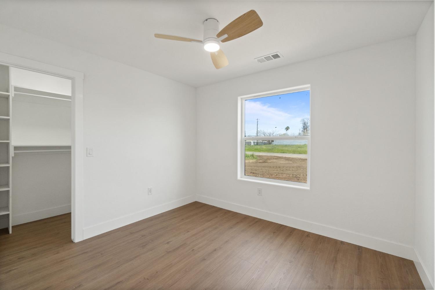 25918 Tanforan Drive Madera, CA 93638 - Photo 23 of 37 an empty room with wooden floor ceiling fan and windows