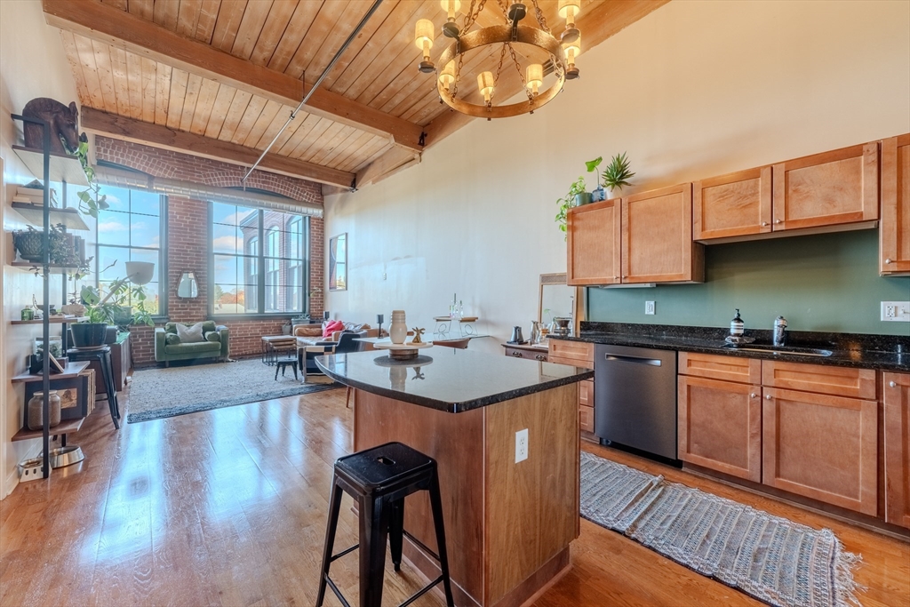 a kitchen with stainless steel appliances granite countertop a sink dishwasher stove and cabinets with wooden floor