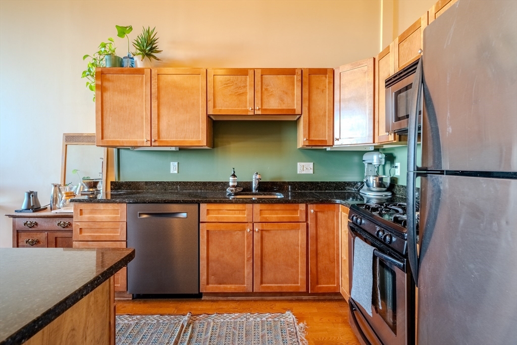 160 Fremont Street, Unit 405 Worcester, MA 01603 - Photo 11 of 34 a kitchen with stainless steel appliances granite countertop a refrigerator a sink dishwasher a stove with wooden cabinets and floor