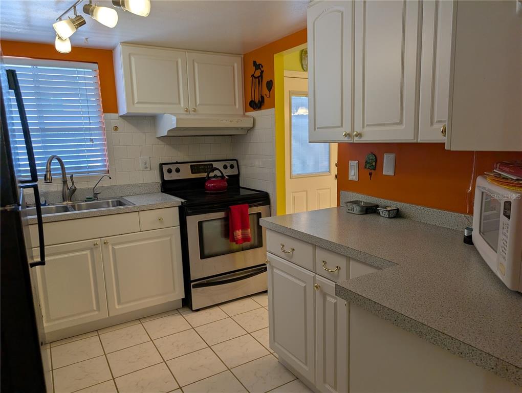 5934 Welcome Road, Unit H7 Bradenton, FL 34207 - Photo 5 of 23 a kitchen with white cabinets and white appliances
