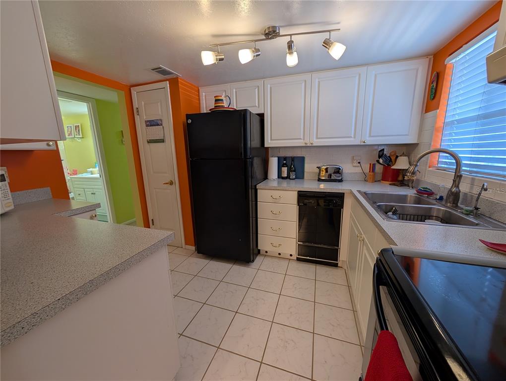 5934 Welcome Road, Unit H7 Bradenton, FL 34207 - Photo 6 of 23 a kitchen with a refrigerator a sink dishwasher and a stove top oven with wooden cabinets