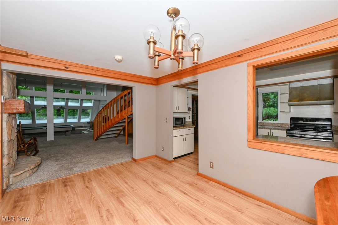 7061 Cascade Road Painesville, OH 44077 - Photo 33 of 49 Kitchen featuring an inviting chandelier, range, wall chimney exhaust hood, and light hardwood / wood-style floors