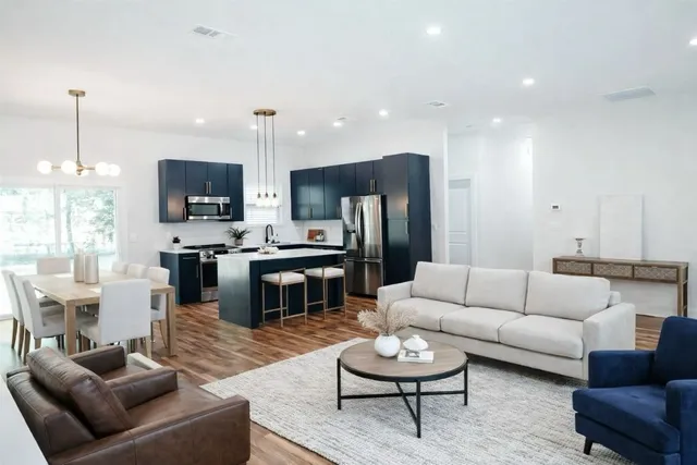 a living room with furniture kitchen view and a chandelier