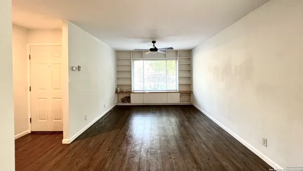 a view of an empty room with wooden floor and a window